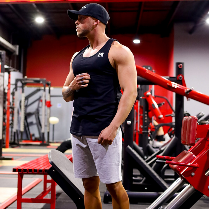 IXK Gear Cotton Stretch Shorts in Grey. Model is also wearing IXK Gear Muscle Tank in Black. Gym background.