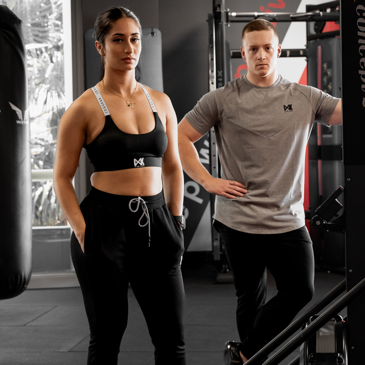 Male model is wearing IXK Gear Cotton Tee in Grey with Slim Sweats in Colour: Black. Female model is wearing IXK Gear X Sports Bra and Cropped Trackies in Black.