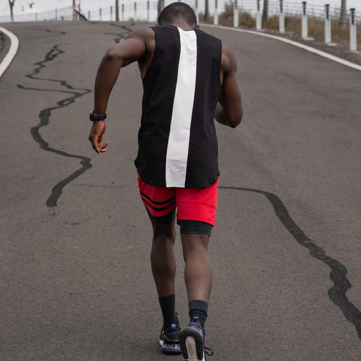 IXK Gear Muscle Tank Top in Black with white quick dry panel at the rear, paired with Quick Dry Accent Shorts in Red. Natural background.