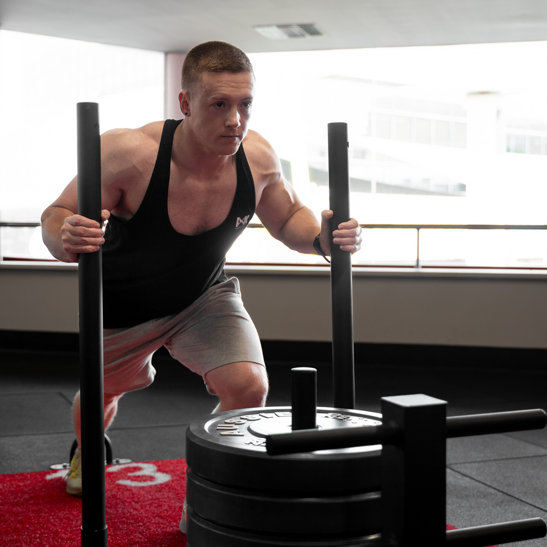 IXK Gear Stringer Tank Top in Colour: Black. Gym Background. Model is also weaaring IXK Gear Cotton Stretch Shorts in Grey