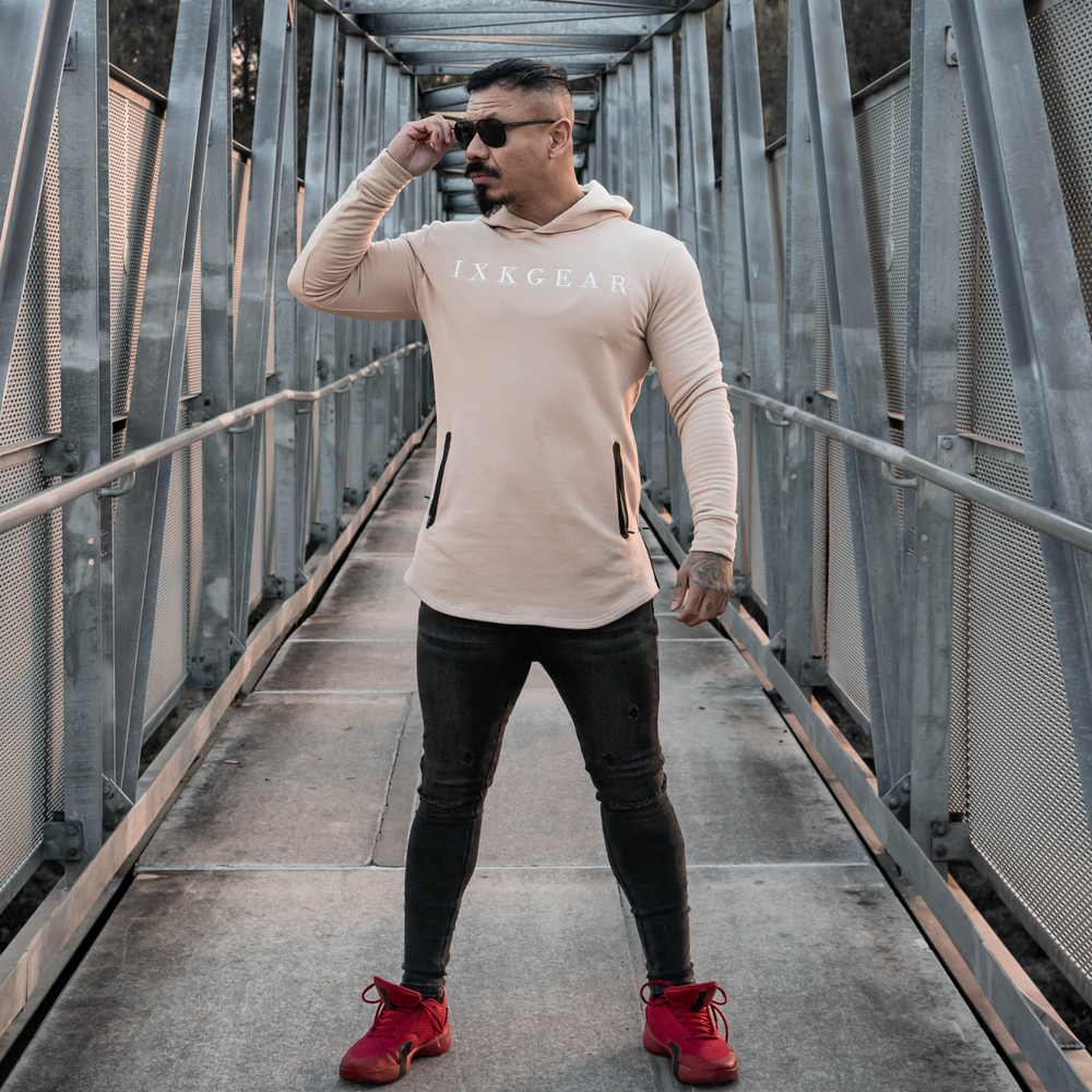 Male model is wearing the IXK Gear Muscle Hoodie in Colour: Sand. Metal Mesh background.