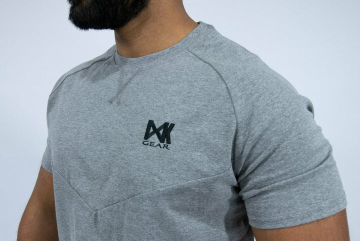 Our IXK Cotton Tee is perfect for intense workouts, errands and rest days. With it's high-quality and sleek finish you'll never want to take it off. Available in Blue/Black/Grey. Close up of chest IXK Gear Logo in Grey Tee.