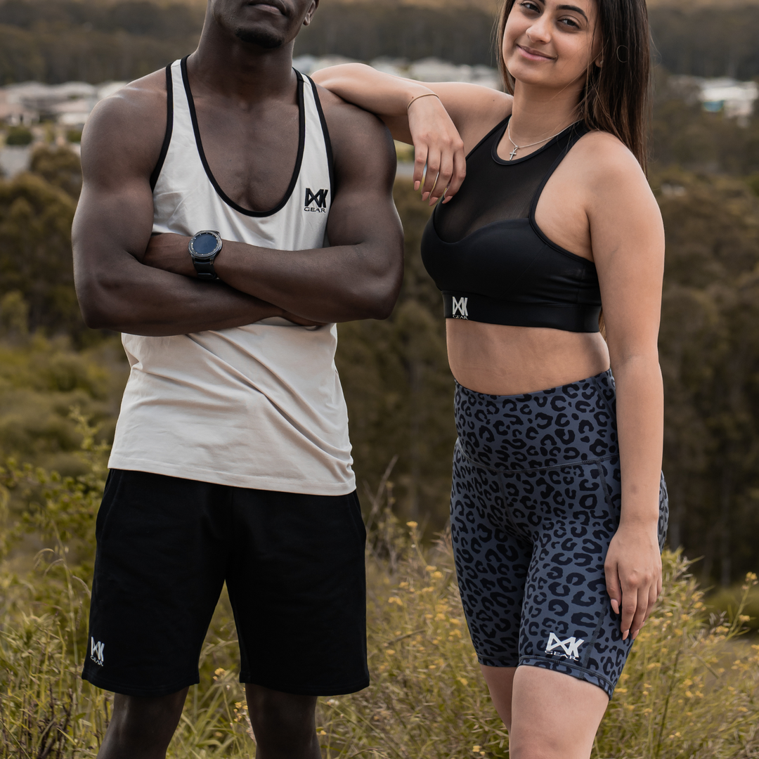 IXK Gear Cotton Stretch Shorts in Black. Model is also wearing IXK Gear Stringer Tank Top in Stone. Femalw model is wearing Mesh Sports Brain Black and Gym Shorts in Dark Grey. Natural background.