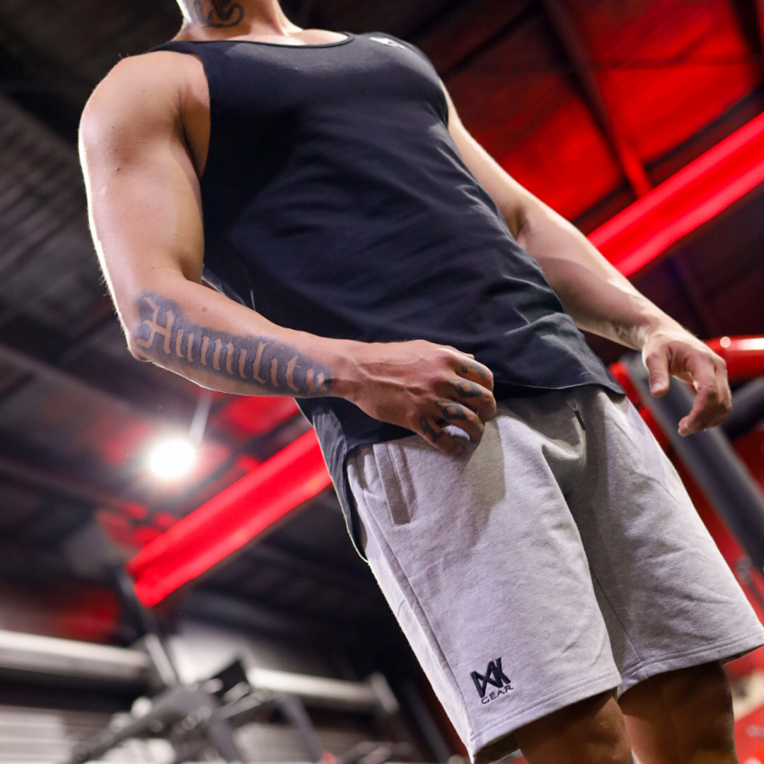IXK Gear Cotton Stretch Shorts in Grey. Model is also wearing IXK Gear Muscle Tank in Black. Gym background.