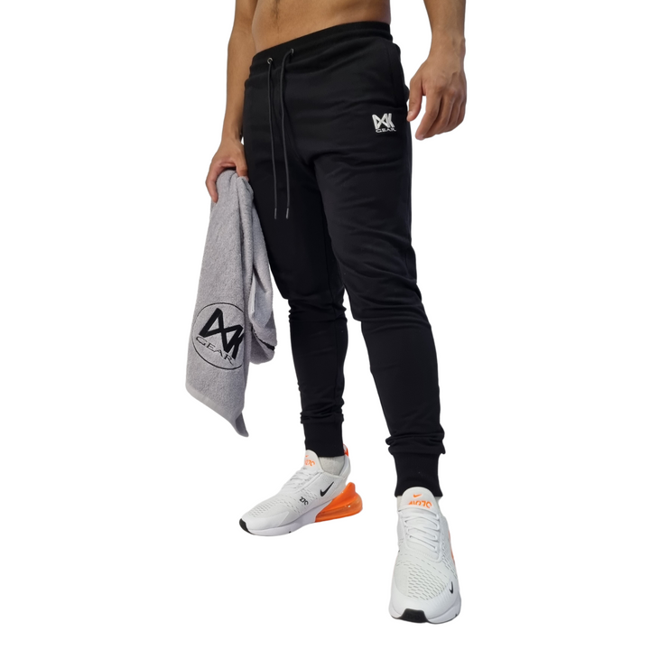 Pictured on model IXK Gear Slim Sweat Trackpant Trackies in Colour: Black. Model is holding the IXK Gear Gym Towel in Grey. Plain White Background.