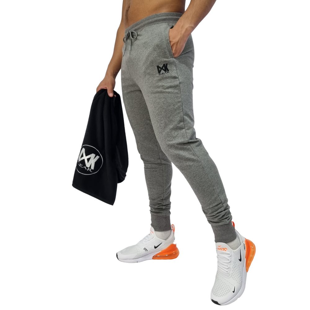Pictured on model IXK Gear Slim Sweat Trackpant Trackies in Colour: Grey. Model is holding the IXK Gear Gym Towel in Black. Plain White Background.