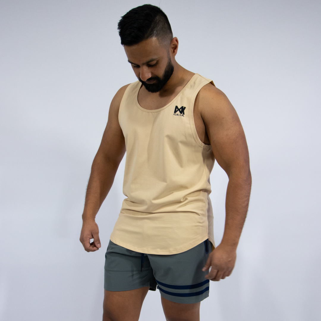 Male model wearing Muscle Tank Top in Colour: Sand, paired with Quick Dry Accent Shorts in Colour: Grey. Plain white background.