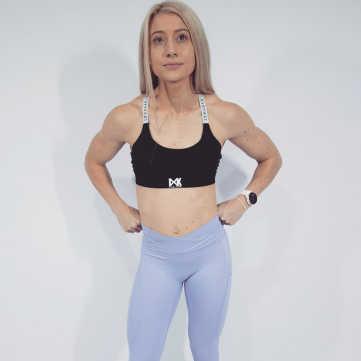 IXK Gear X Sports Bra in Colour: Black. Plain White Background. Model is also wearing NV Tights in Colour: Lavender.