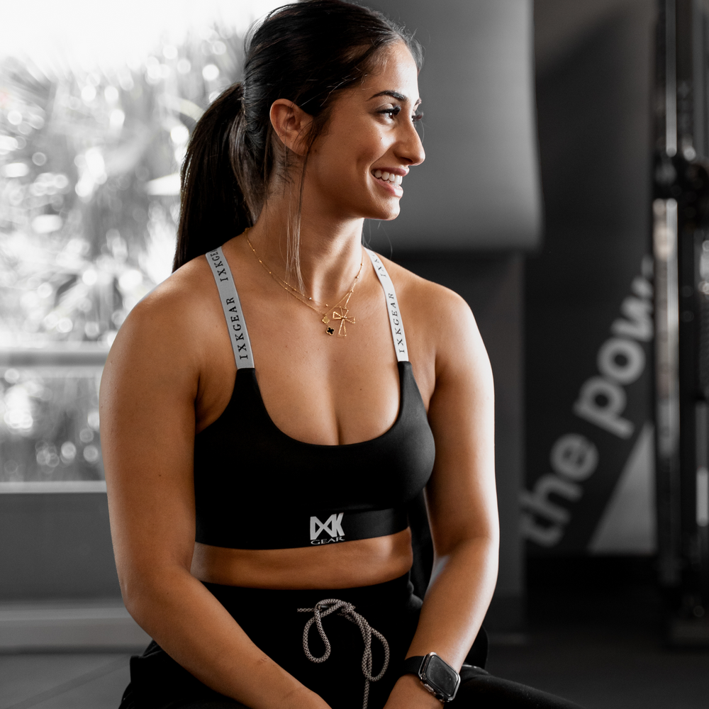 IXK Gear X Sports Bra in Colour: Black. Model is also wearing Cropped Trackies in Colour Black. Gym Background.