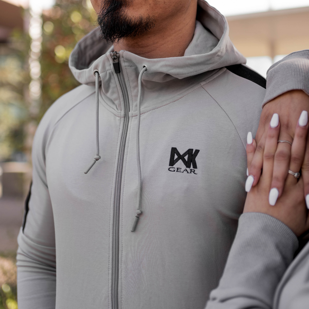 Model is wearing the complete IXK Gear Men's Tracksuit in Colour: Stone. Close up of the Hooded Jacket of the tracksuit set. Natural Background.